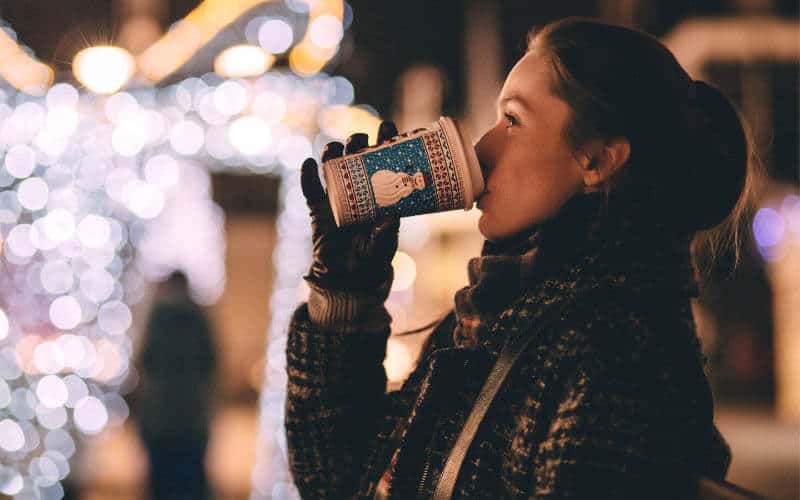 Woman drinking coffee outside at Christmas market