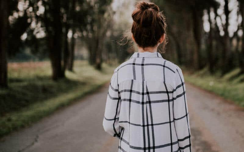 dark haired woman walking down country road