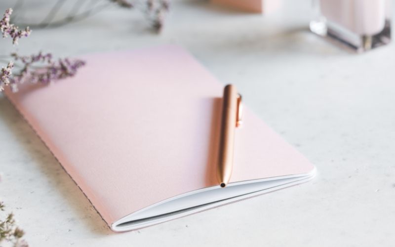 light pink journal and gold pen on desk