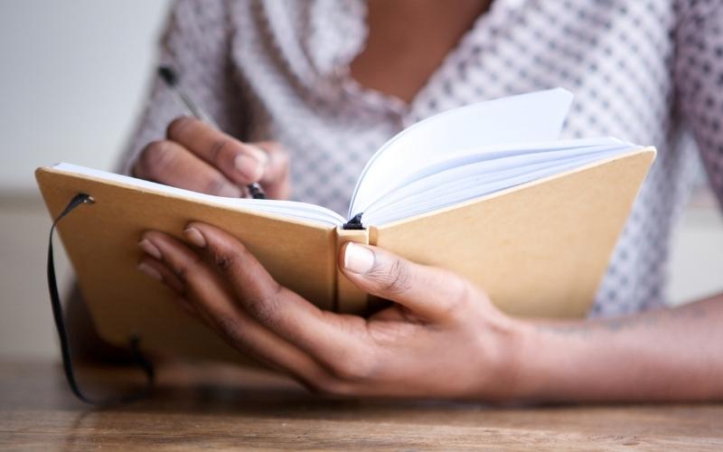 closeup of women writing in journal