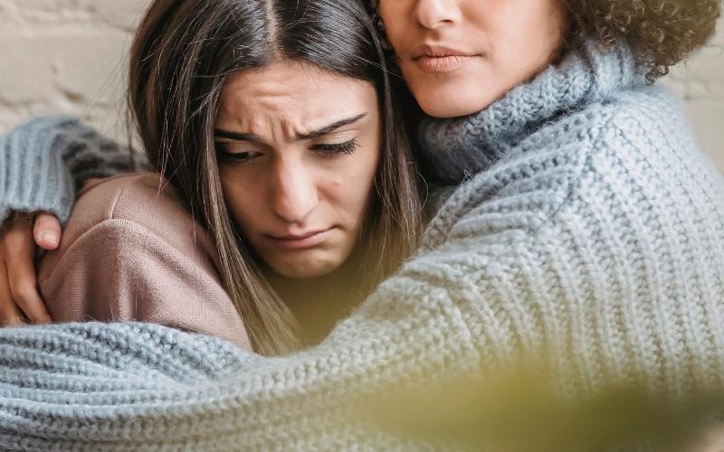 friend hugging woman who's going through a tough time